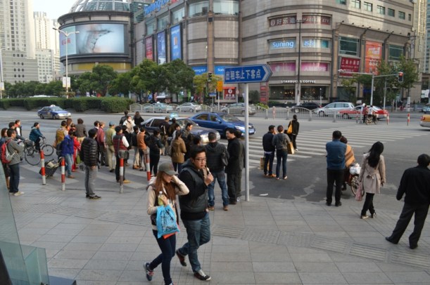 People standing around waiting in the middle of the road.